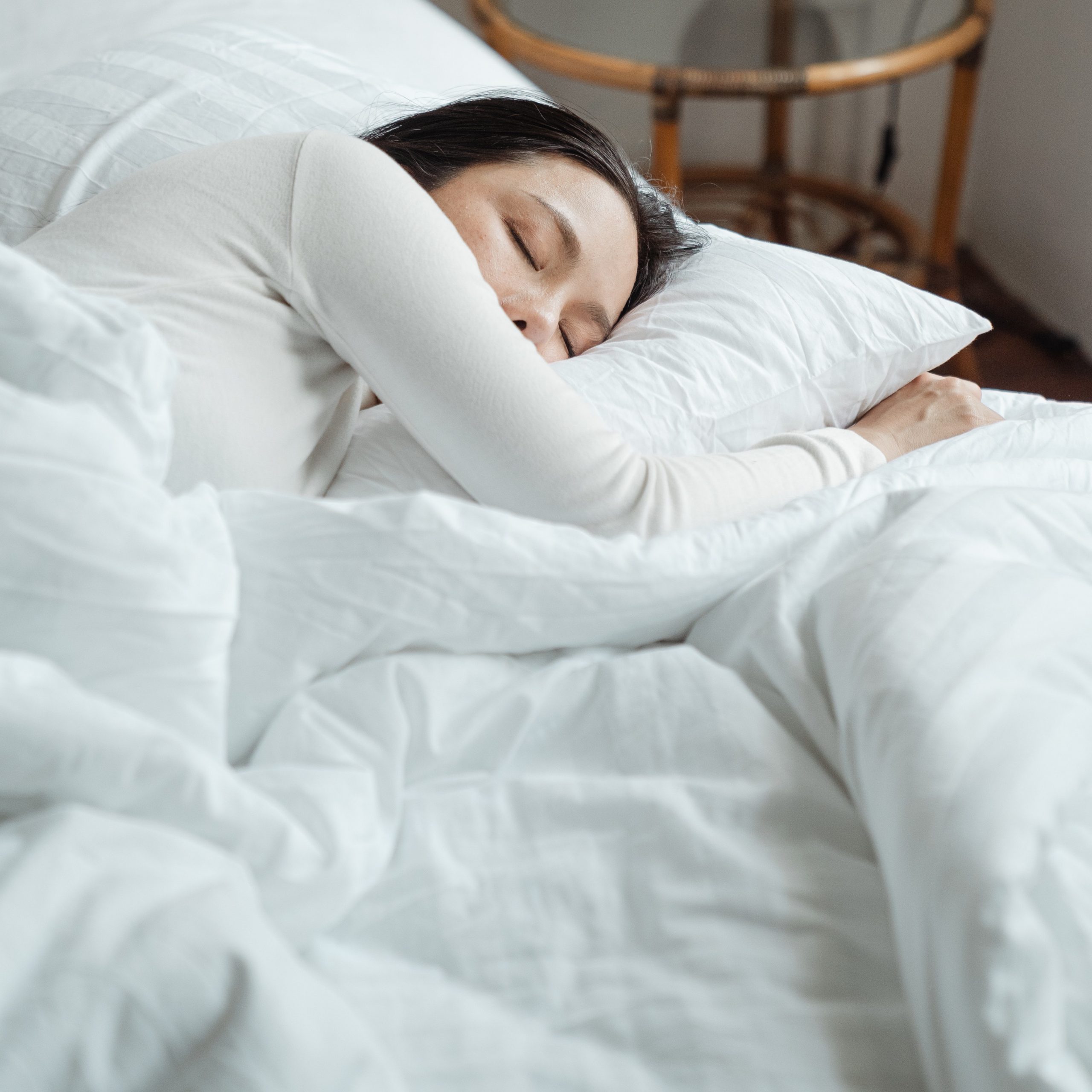Nainen nukkuu sängyssä valkoisissa lakanoissa