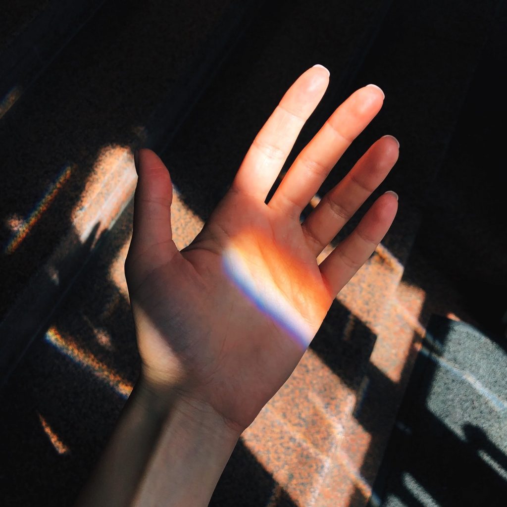 Hand in rainbow sun